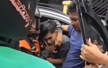 Tangkapan layar video memperlihatkan seorang pemuda di Makassar diseret keluar dari mobil dan menjadi sasaran amukan massa.