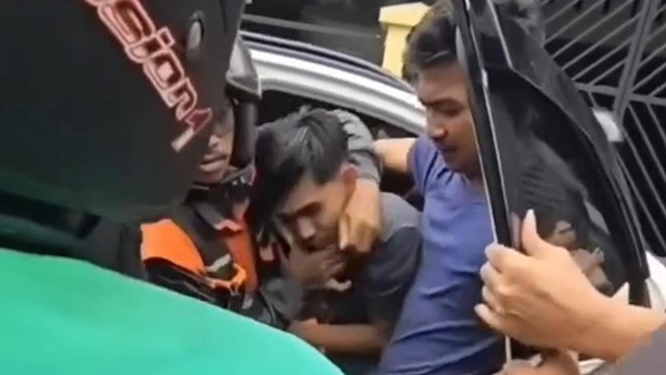 Tangkapan layar video memperlihatkan seorang pemuda di Makassar diseret keluar dari mobil dan menjadi sasaran amukan massa.