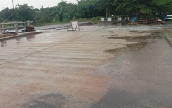 Kondisi ruas jalan dan jembatan yang diduga bagian dari proyek Riverside Road Project (RRP) di kawasan Antang, Makassar, tampak basah usai hujan, dengan pembatas darurat terpasang di lokasi yang disorot terkait dugaan pelanggaran lingkungan dan perizinan.
