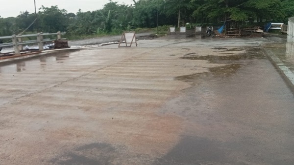 Kondisi ruas jalan dan jembatan yang diduga bagian dari proyek Riverside Road Project (RRP) di kawasan Antang, Makassar, tampak basah usai hujan, dengan pembatas darurat terpasang di lokasi yang disorot terkait dugaan pelanggaran lingkungan dan perizinan.