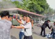 Sejumlah pria berpakaian sipil bersama oknum petugas berseragam putih terlibat aksi saling tarik saat berupaya mengamankan seorang mahasiswa di tanah. Insiden mencekam ini terjadi di tengah aksi unjuk rasa AMPH terkait darurat narkoba yang berakhir rusuh.