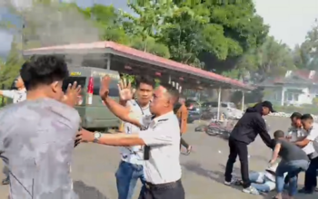 Sejumlah pria berpakaian sipil bersama oknum petugas berseragam putih terlibat aksi saling tarik saat berupaya mengamankan seorang mahasiswa di tanah. Insiden mencekam ini terjadi di tengah aksi unjuk rasa AMPH terkait darurat narkoba yang berakhir rusuh.
