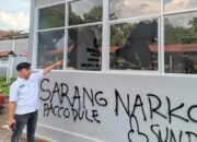 Petugas Lapas menunjuk kaca bangunan yang pecah serta coretan pilox di dinding pasca-aksi demonstrasi AMPH, Senin (25/5/2026). Coretan bertuliskan "Sarang Narkoba” tersebut mempertegas substansi tuntutan massa yang kini diduga kuat berusaha dikaburkan oleh pihak otoritas penjara. (Ist)