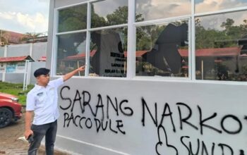 Petugas Lapas menunjuk kaca bangunan yang pecah serta coretan pilox di dinding pasca-aksi demonstrasi AMPH, Senin (25/5/2026). Coretan bertuliskan "Sarang Narkoba” tersebut mempertegas substansi tuntutan massa yang kini diduga kuat berusaha dikaburkan oleh pihak otoritas penjara. (Ist)