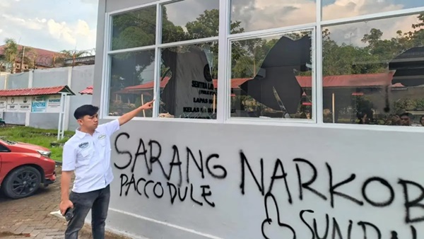 Petugas Lapas menunjuk kaca bangunan yang pecah serta coretan pilox di dinding pasca-aksi demonstrasi AMPH, Senin (25/5/2026). Coretan bertuliskan "Sarang Narkoba” tersebut mempertegas substansi tuntutan massa yang kini diduga kuat berusaha dikaburkan oleh pihak otoritas penjara. (Ist)